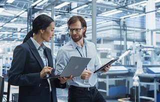 Two professionals discussing inventory in smart manufacturing.