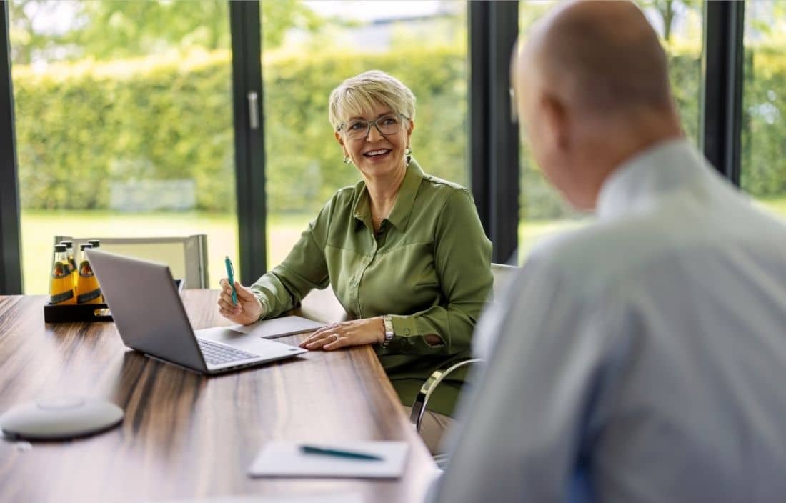 Senior adult smiling and taking notes.