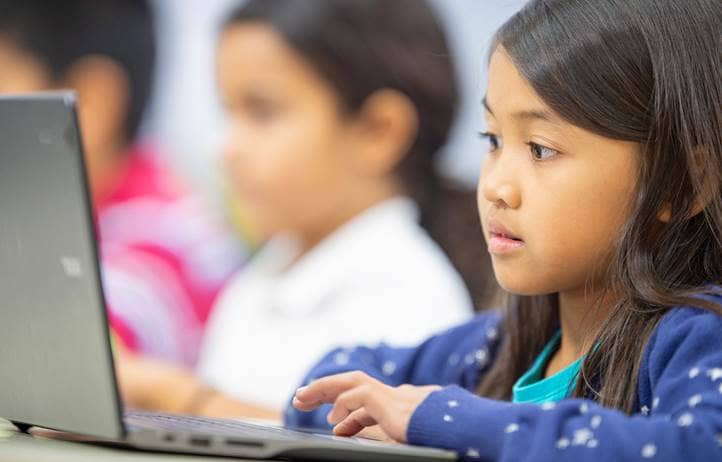 Young child working on their laptop in school.