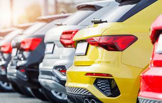 View of backends and bumpers of cars in a parking lot