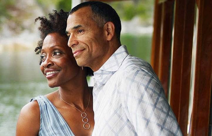 Wealthy couple smiling and looking out their window.