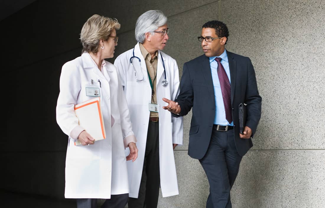 Business professional walking with two doctors in white coats.
