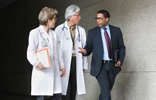 Business professional walking with two doctors in white coats.