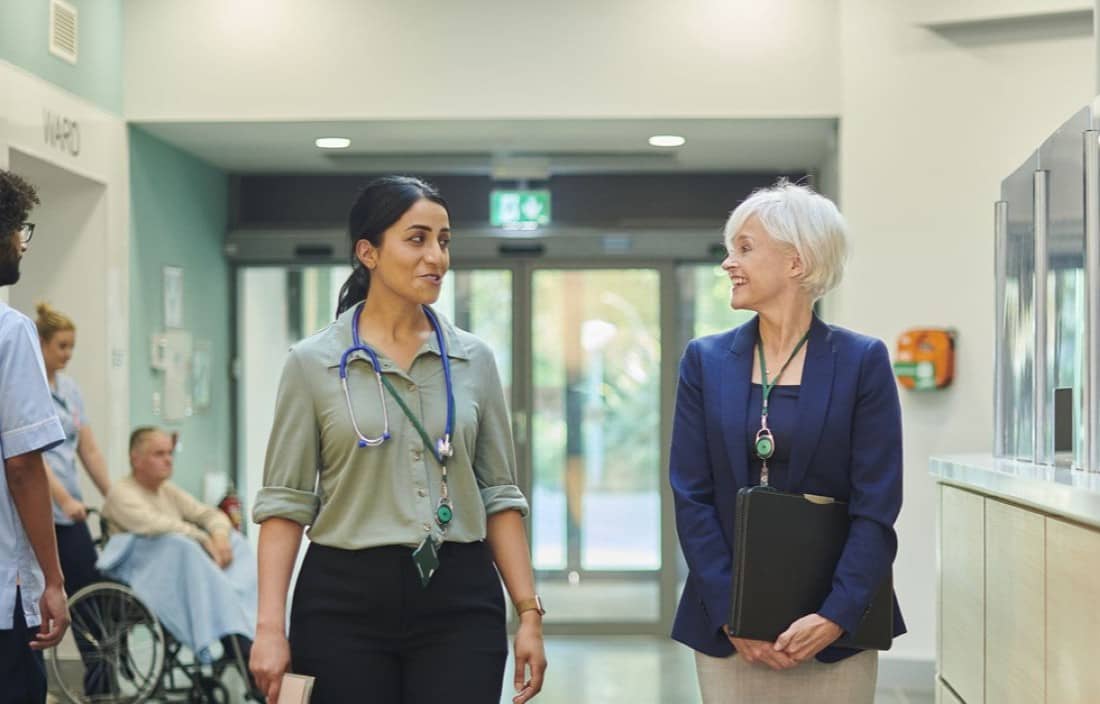 Medical sales representative walking down a hospital hallway with a doctor,