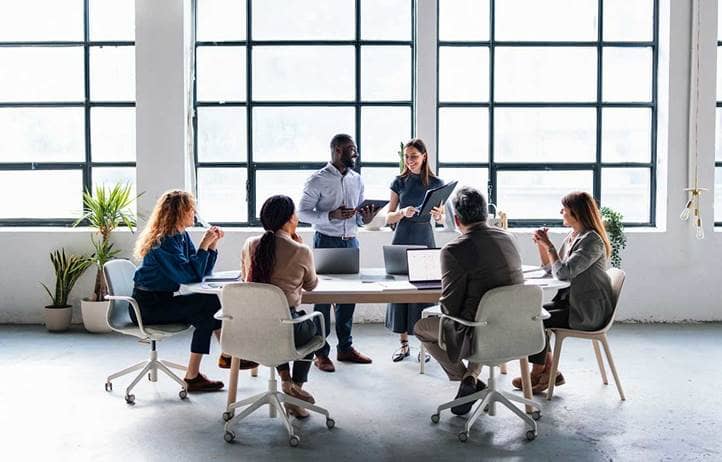 Group of business professionals discussing post-acquisition reporting in a modern office.