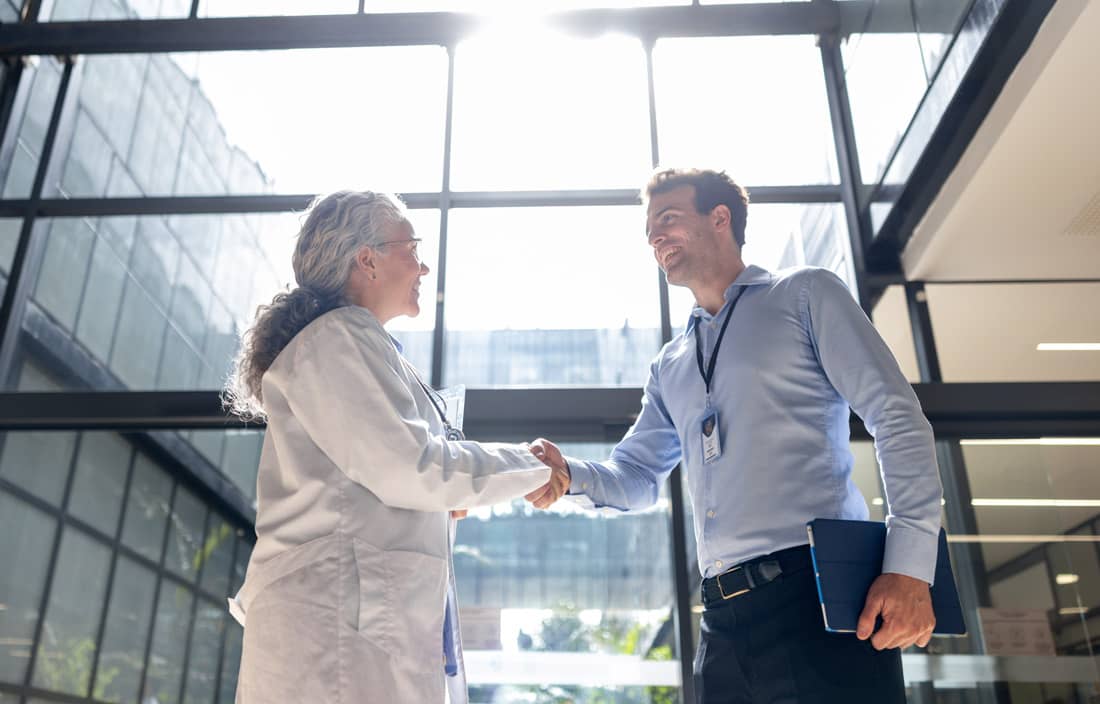 Healthcare professionals shaking hands in a hospital lobby.