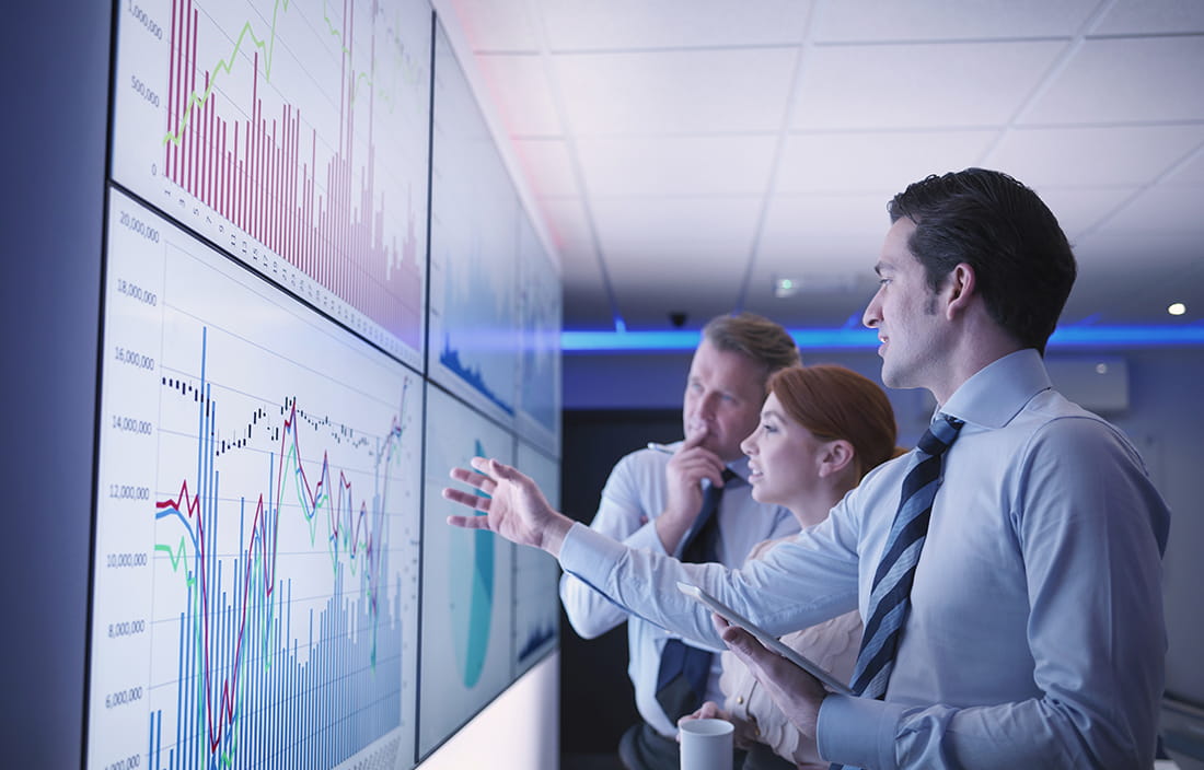 Business colleagues studying a chart together on a TV screen.