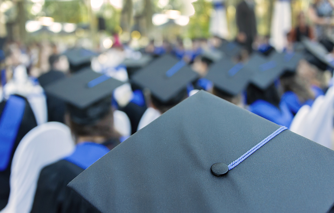 Up close picture of people wearing graduation caps at a graduation