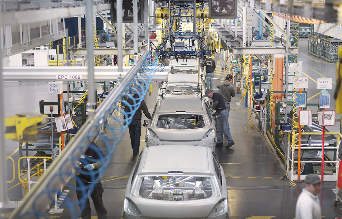 Automotive workers inside a factory building cars