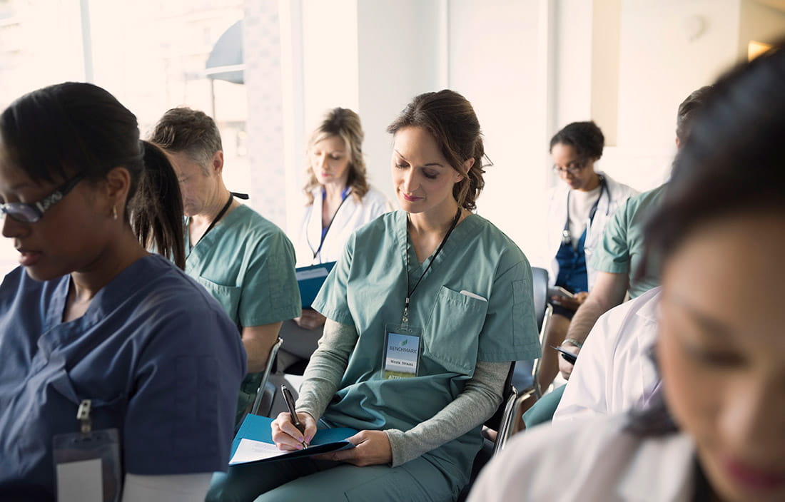 Nurses sitting in scrubs, taking notes