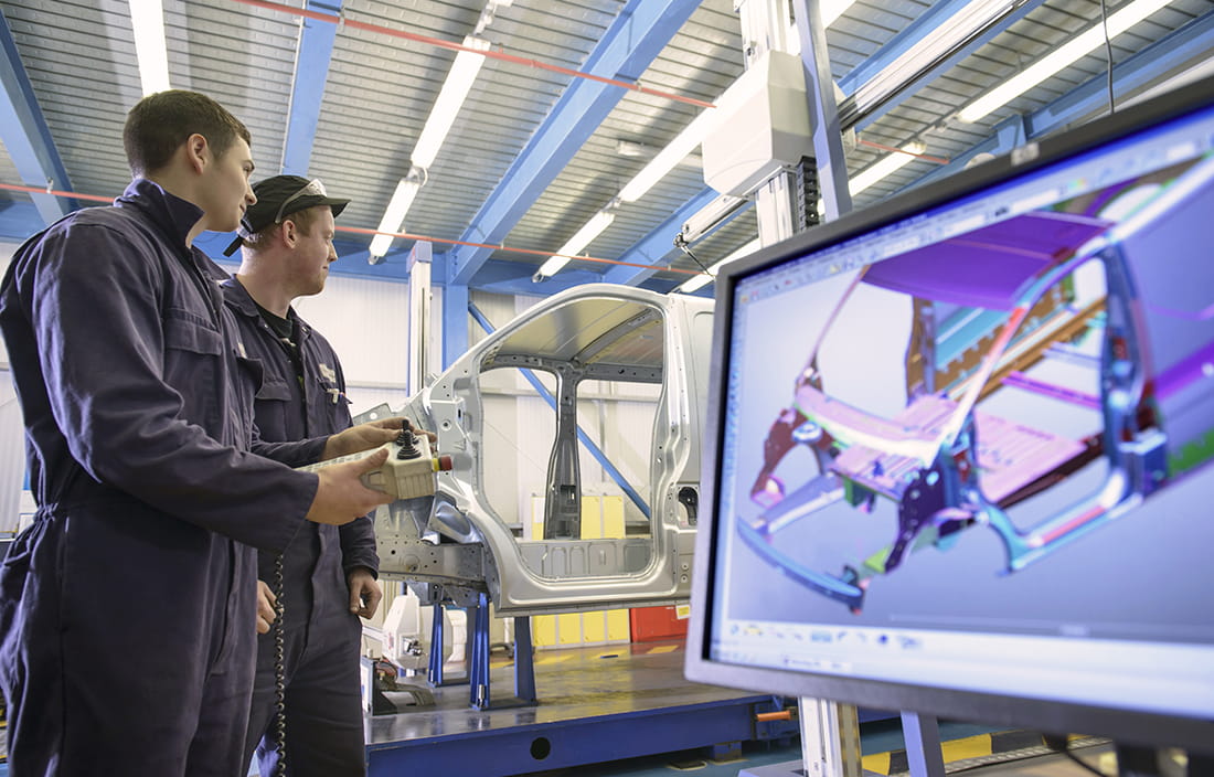 Two men working on a car door in an auto plant