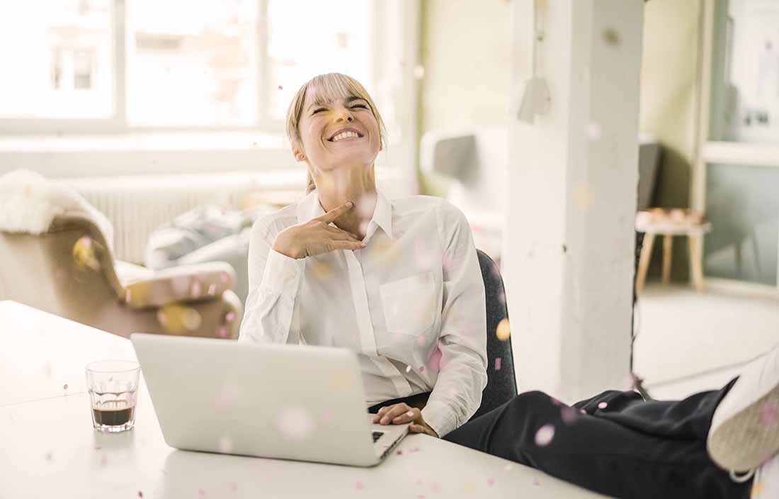 A woman laughing while sitting with her laptop