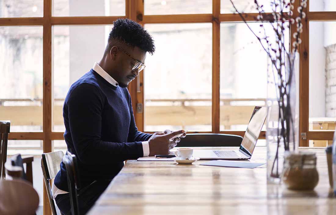 Man sitting at a table with his laptop and phone