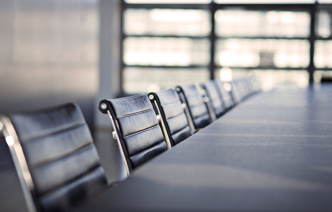 Close-up photo of a conference room with board member chairs.