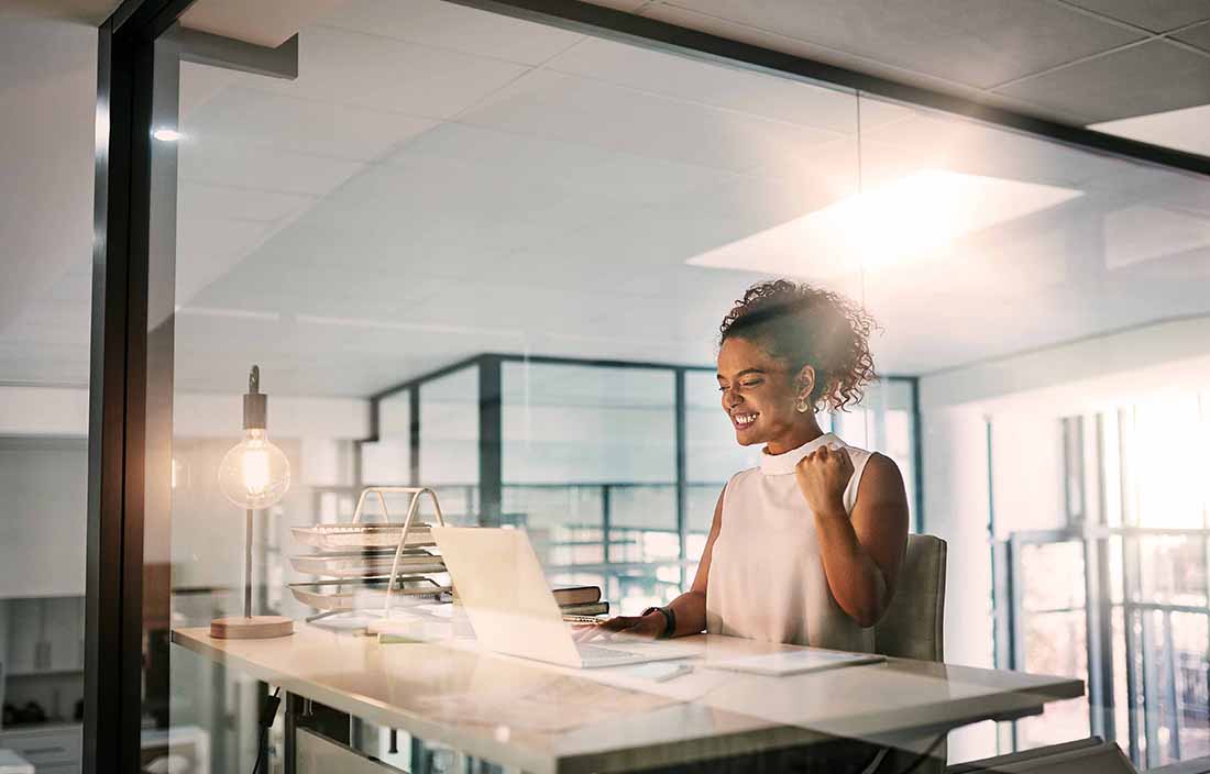 Woman cheering at desk with laptop