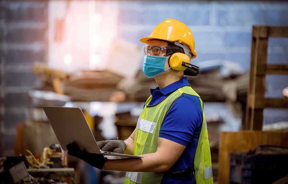 Factory worker in a mask on a laptop