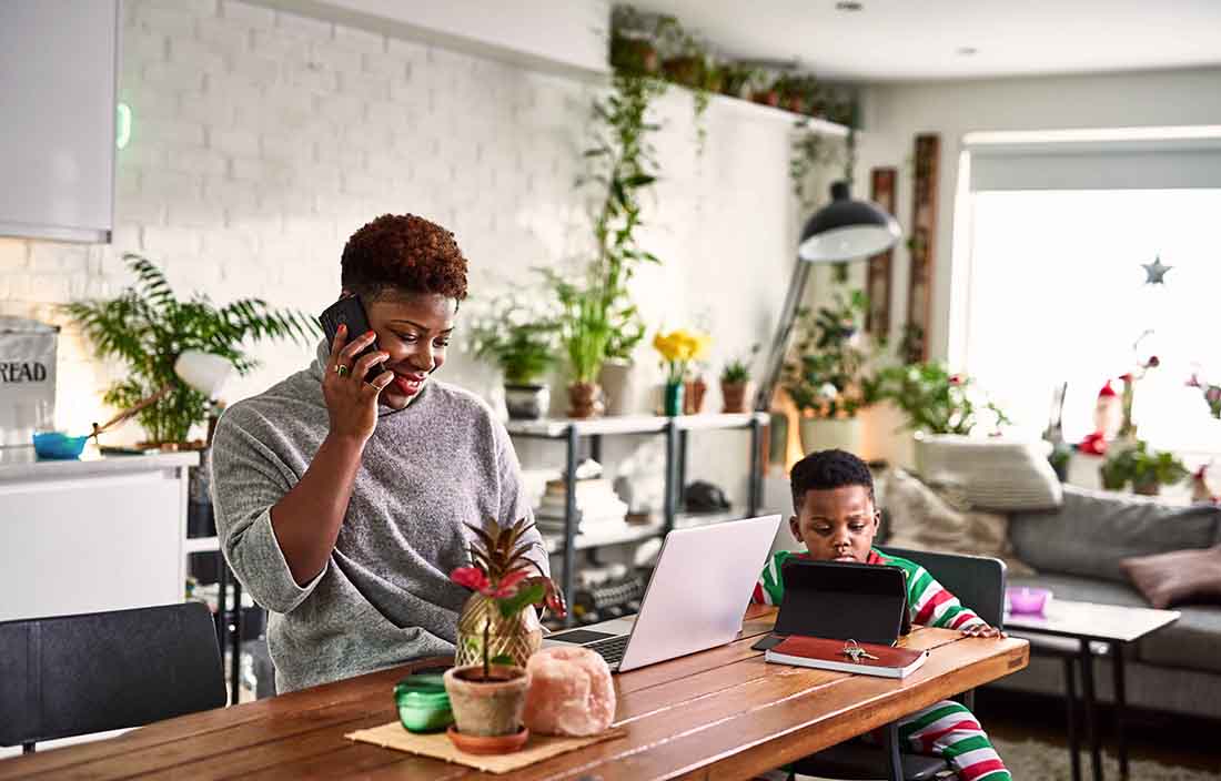 Woman and child sitting at a table on their tablets