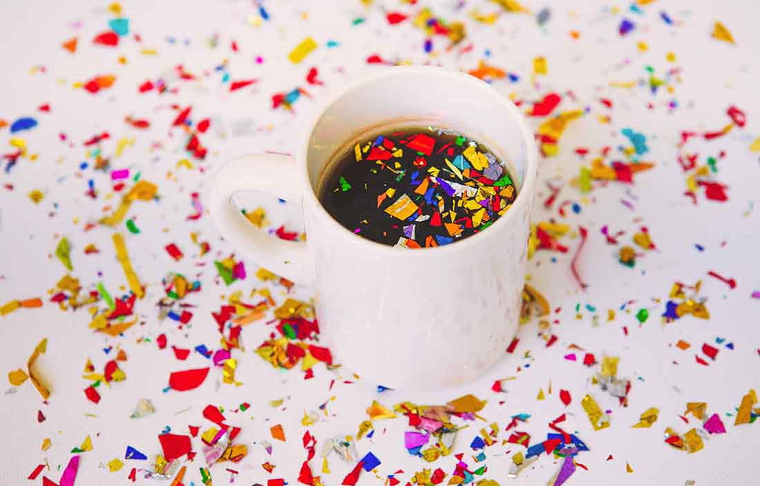 Close-up of a cup of coffee with party confetti around it.