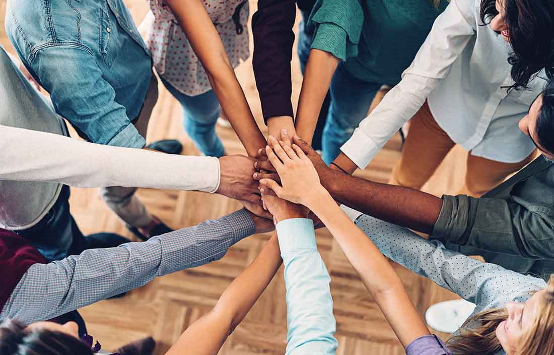 Close-up of hands stacked on top of each other for a celebratory bring it in.