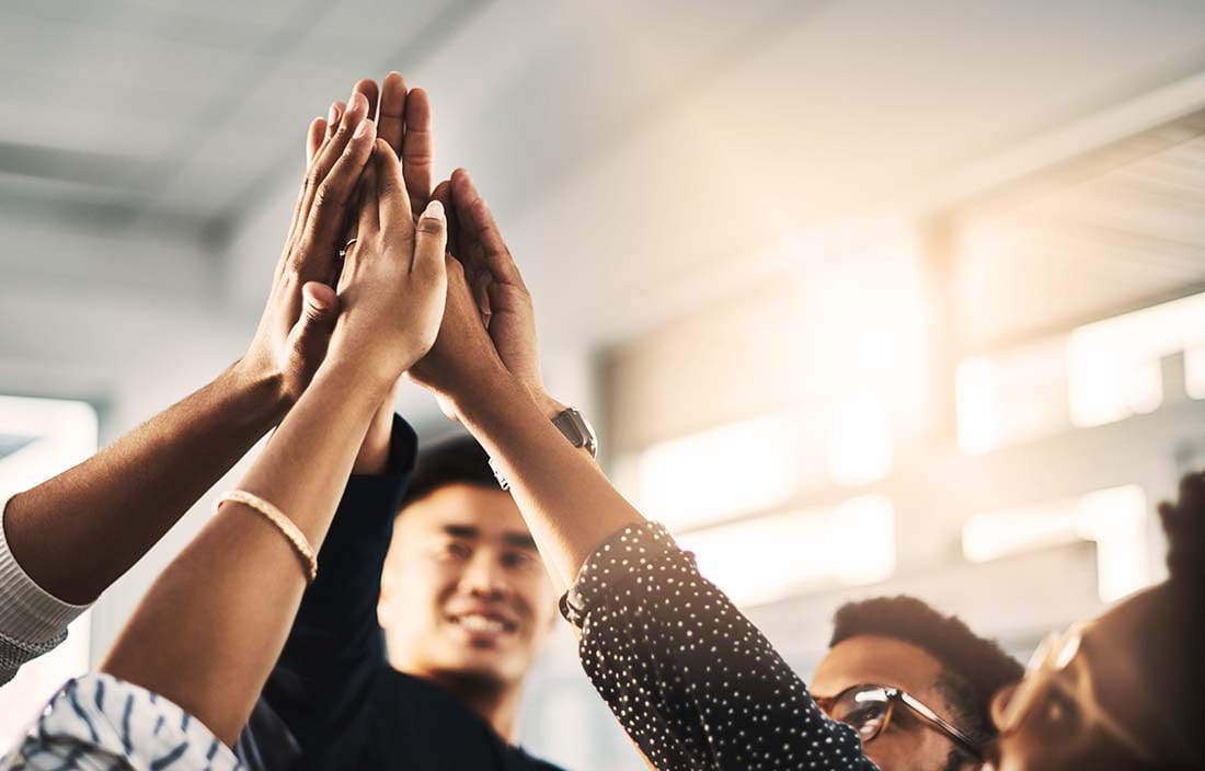 Business professionals putting hands together in a celebration.