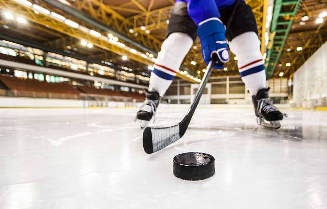 Close-up view of a hockey player with a hockey stick and hockey puck.