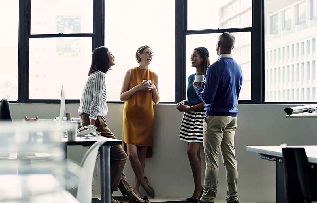 Business professionals in casual business attire laughing and smiling in the office.