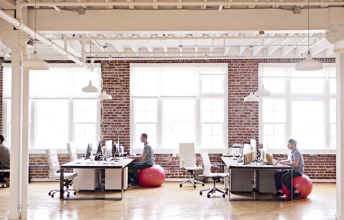 Business professionals in an office sitting on balance balls for their office chairs.