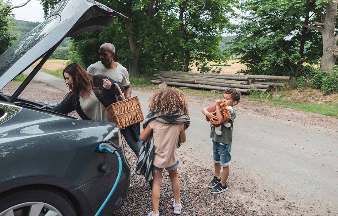 Family loading the back of car together with supplies.