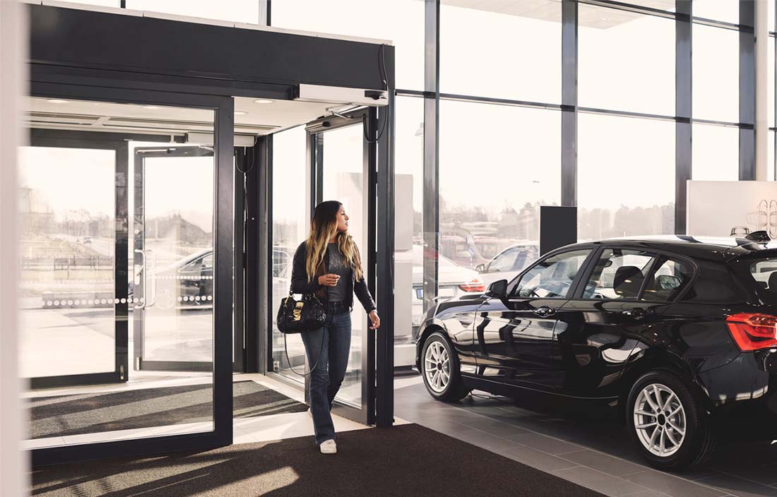 Woman walking into a car dealership.