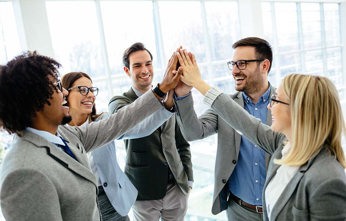 Business professionals raising their hands together in a celebratory pose.