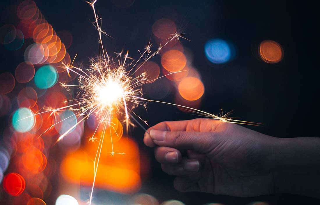 Close-up photo of a hand holding a sparkler firework.