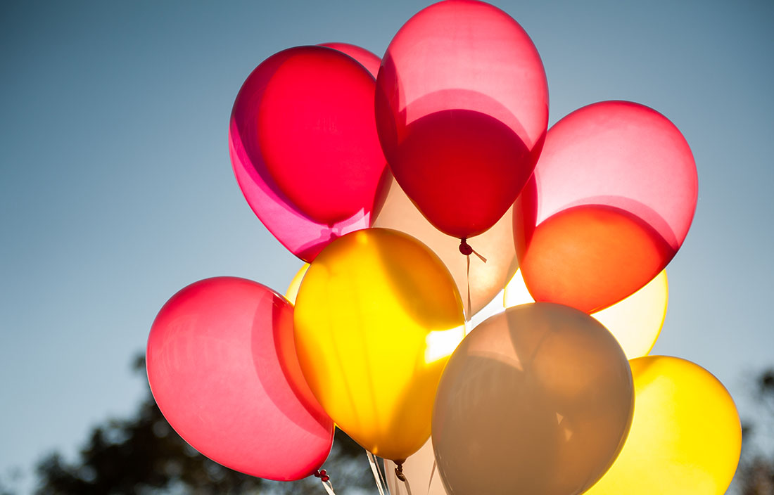 Cluster of pink and yellow balloons in the sky.