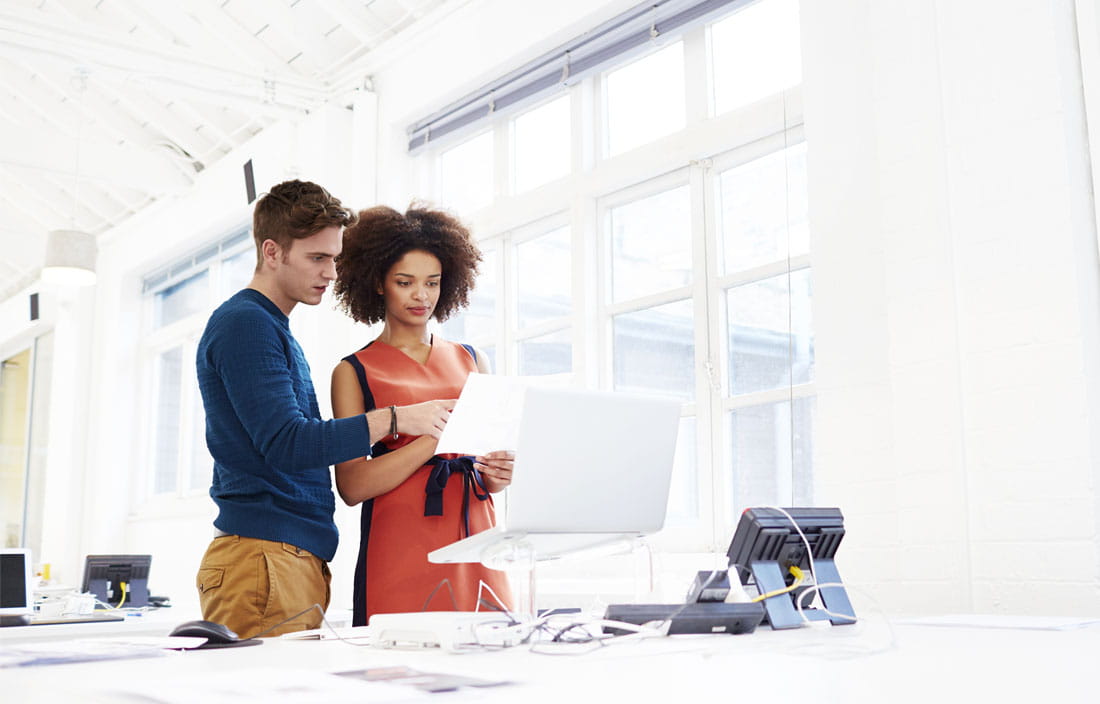 Two business professionals looking at information on a laptop screen.