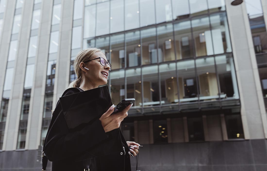 Image of a business professional walking down a city street holding their cell phone.