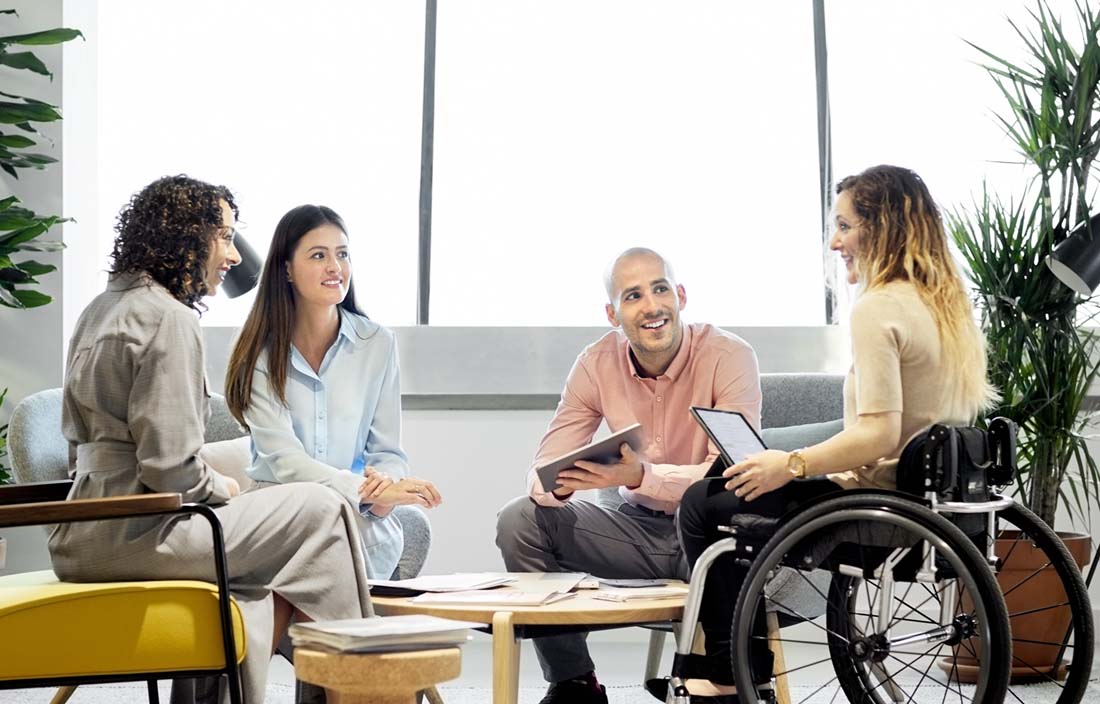 Group of coworkers gathered around table in discussion.