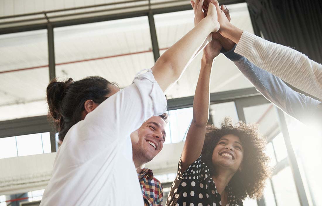 Group of coworkers raising hands in celebration.