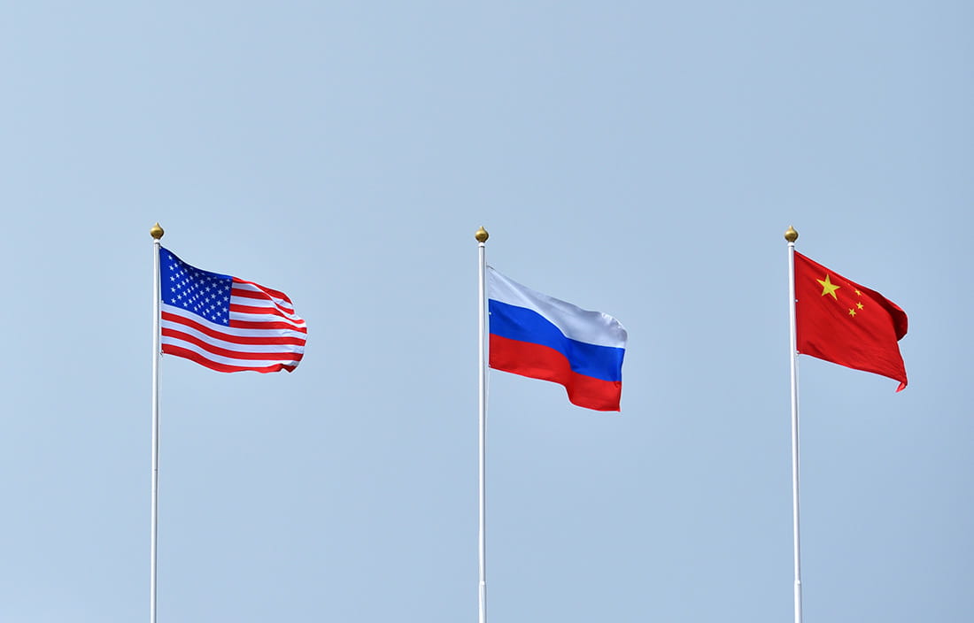 American, Russian, and Chinese flags against a blue sky.