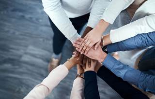 Group of coworkers putting their hands together.