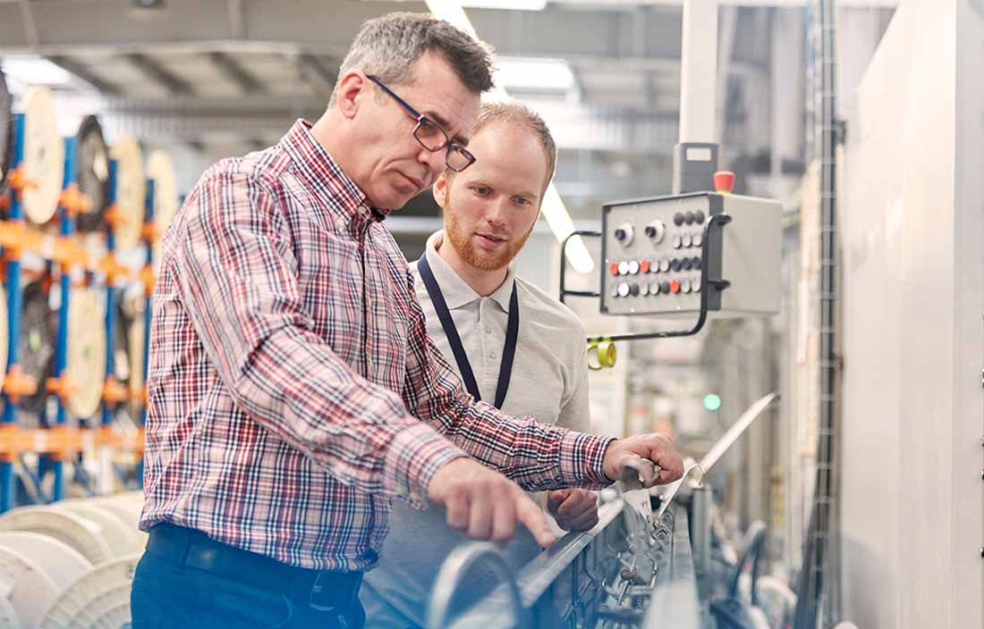 Two factory workers inspecting factory machine.