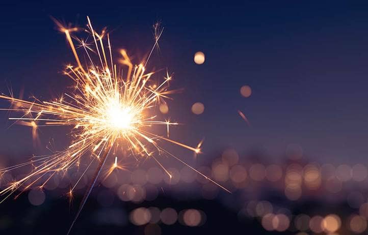 Sparkler in front of blurry image of commercial buildings