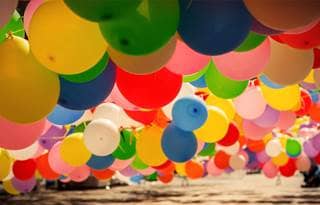 Colored balloons hung in lines from strings over what appears to be water