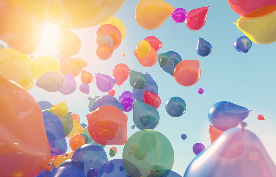 Colorful balloons rising up loose into the air on a sunny, clear sky