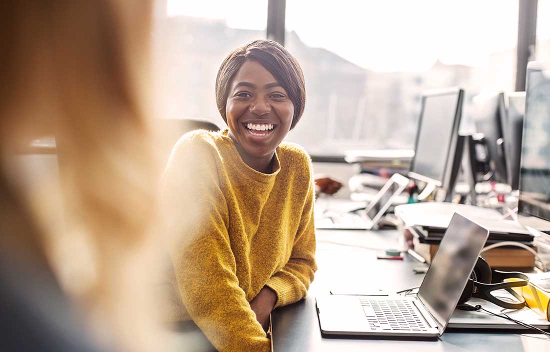 Office workers at a manufacturing and technology company laughing in a brightly lit office