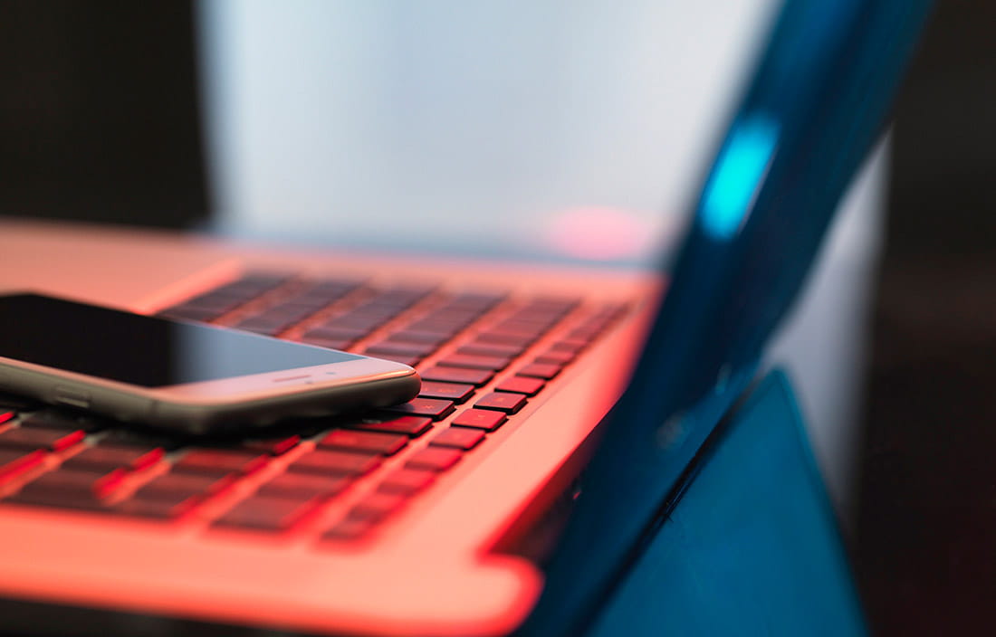 Close-up photo of a laptop and smart phone in dim light