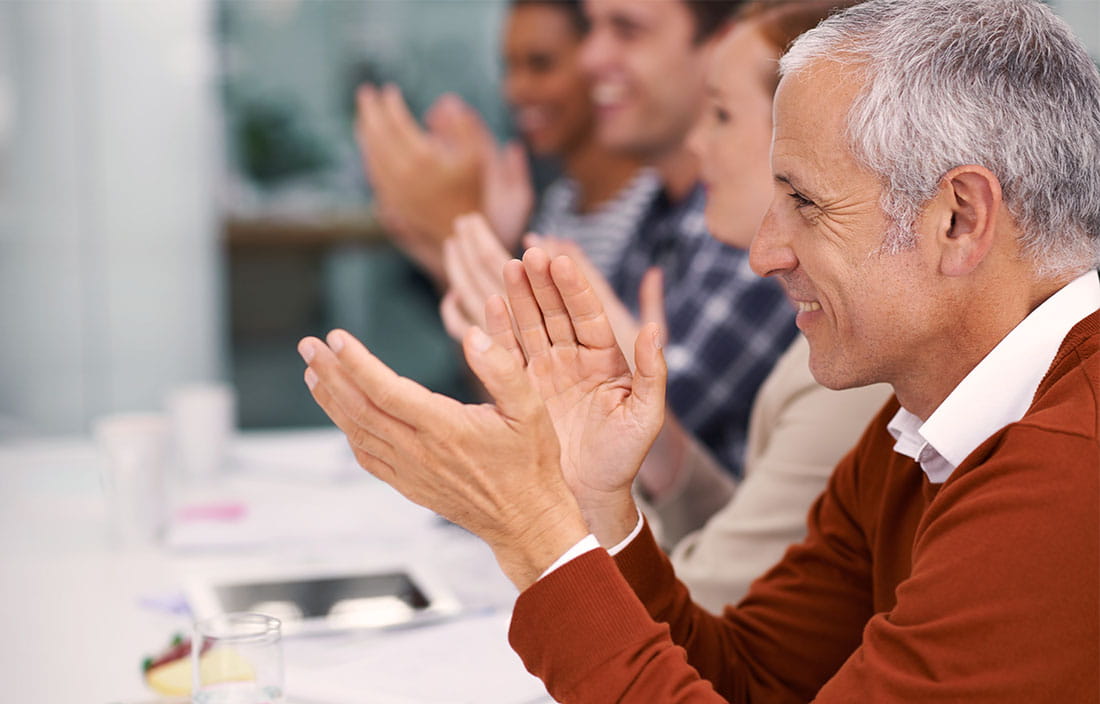 Man and others in background clapping and smiling