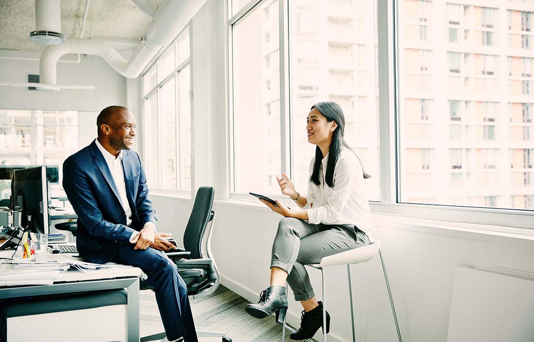 Two professionals sitting in their modern office discussing business