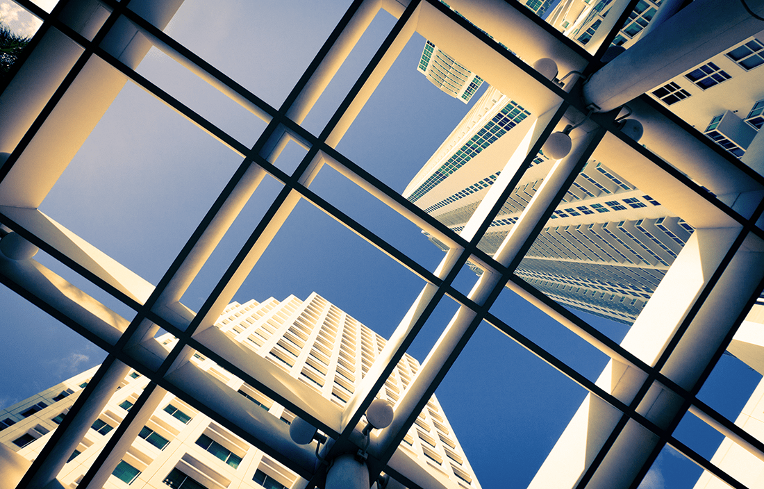 View up through a skylight to see a skyscraper against a blue sky