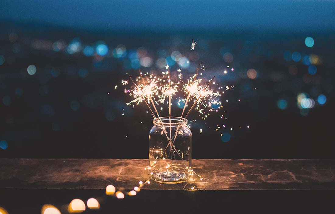 Celebration of staff promotions or new hires with sparklers in a mason jar overlooking a city scape