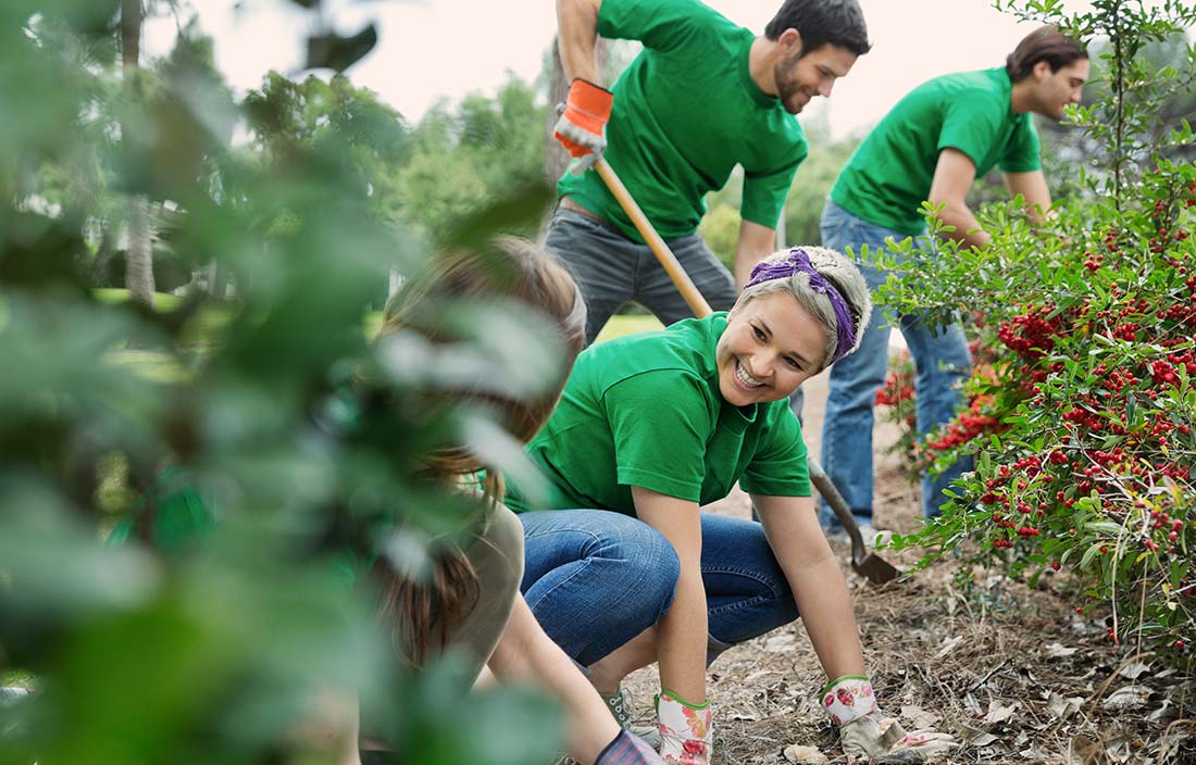 candid shot of people volunteering to clean up outdoor area