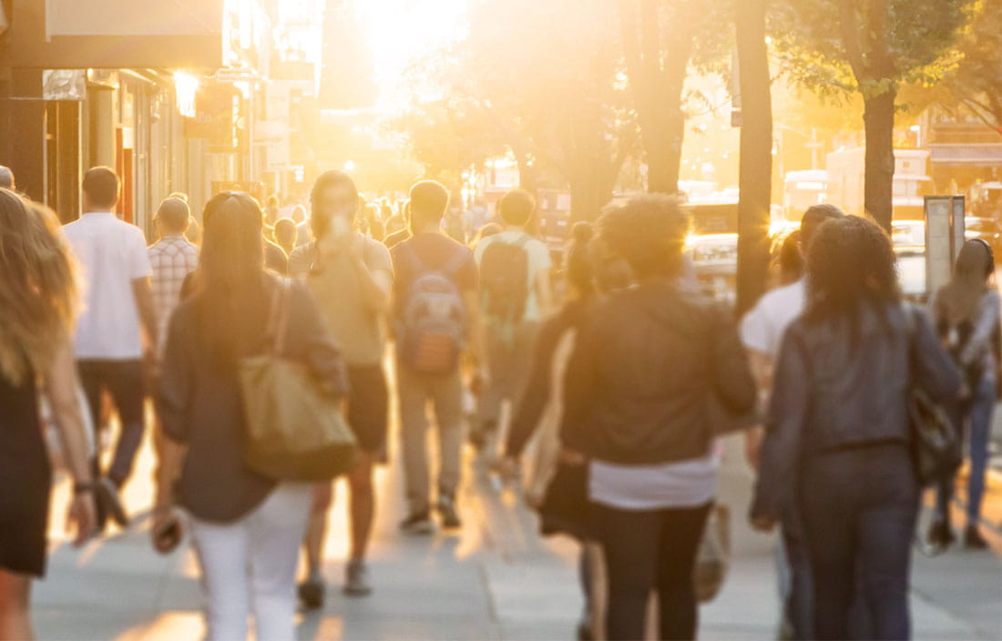 Crowd of people walking down sidewalk in a city after a successful development project